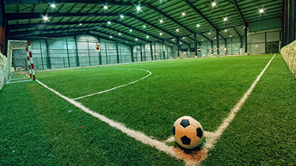 soccer ball sitting at the corner of an indoor soccer field